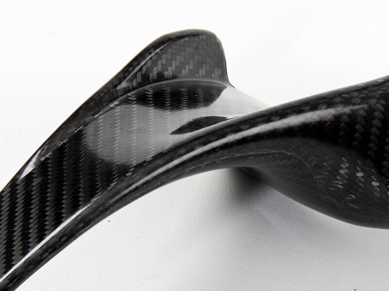 HANS device laying down on a white surface. The carbon fiber surface of the composite bladder molded structure is a weave with a glossy finish. This image highlights the curved section, as the head and shoulder section transition to the chest panels. 